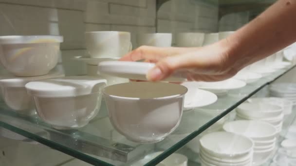 A woman buys dishes in the store, examines various items of dishes. — Stock Video
