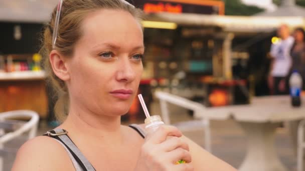 Устал от жары девушка пьет холодный коктейль через соломинку, крупным планом — стоковое видео
