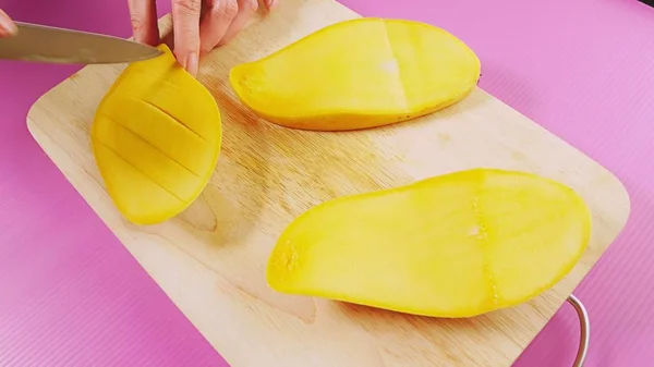トップ ビュー女性手木の板にナイフで果物をカット マンゴー。自然健康食品のコンセプト. — ストック写真