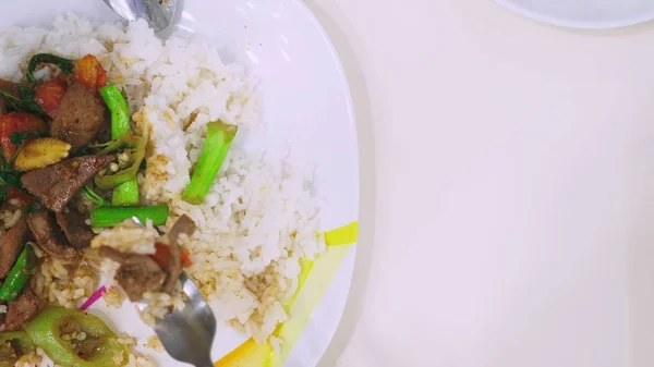 Alguien come con un tenedor, arroz con hígado, comida vista superior en un plato blanco . —  Fotos de Stock