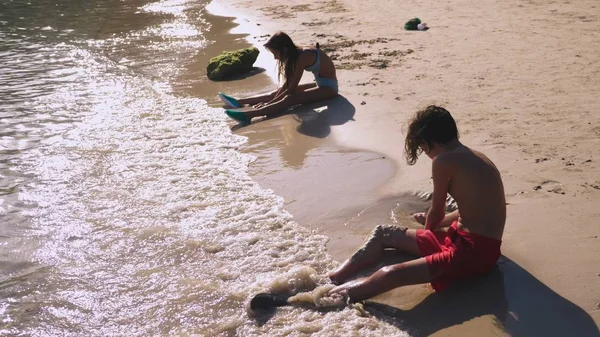 Οι έφηβοι, αδελφός και αδελφή κάνοντας ένα κάστρο σε μια τροπική παραλία με άμμο — Φωτογραφία Αρχείου