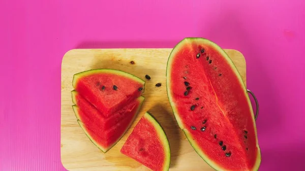 Vista superior, a mão feminina corta frutas com uma faca em uma tábua de madeira, melancia vermelha. O conceito de comida saudável natural . — Fotografia de Stock