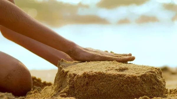 Girl builds a sand castle on a tropical beach. close-up — Stock Photo, Image