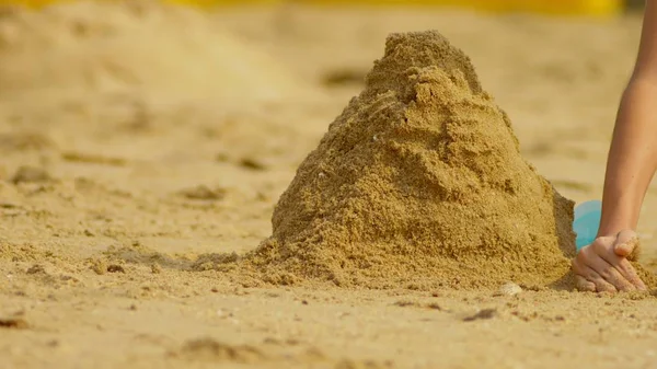 Meisje bouwt een zandkasteel op een tropisch strand. Close-up — Stockfoto