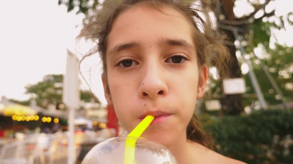Tired of the heat the girl drinks a cold cocktail through a straw, close-up — Stock Photo, Image