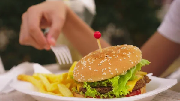 Teenie-Junge isst Hamburger und Pommes im Outdoor-Café. Nahaufnahme — Stockfoto