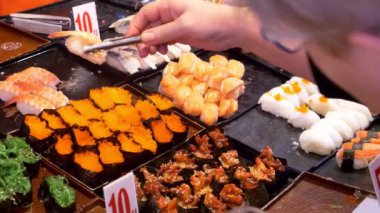 Asya mutfağı, gıda kavramı. kapatın. maşa ile el suşi gece piyasada sokakta seçin..