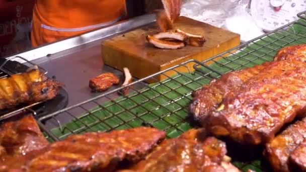 Cocina asiática, concepto de comida. Cerca. Costillas de cerdo barbacoa en el mostrador en el mercado nocturno en la calle . — Vídeos de Stock