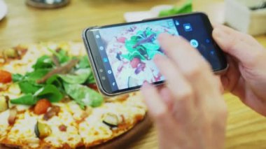 yakın çekim. Eller Smartphone cep telefonu ile restoranda pizza fotoğrafını çekin.