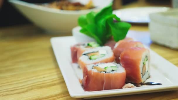 Крупным планом. палочки для еды, берущие суши с тарелки в ресторане — стоковое видео