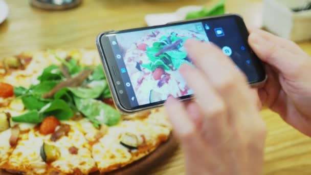 Крупным планом. Женщины фотографируют пиццу на смартфоне в ресторане . — стоковое видео