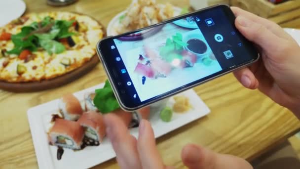 Primer plano. Las manos femeninas toman una foto de sushi en un teléfono inteligente en un restaurante . — Vídeo de stock