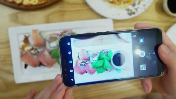 Крупним планом. Жіночі руки фото суші на смартфоні в ресторані . — стокове відео