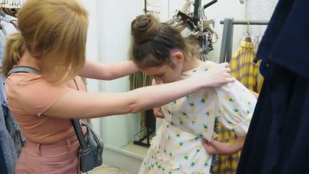 Mère et fille choisissent de nouveaux vêtements dans le magasin de vêtements pour enfants — Video