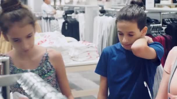 Anya és lánya válasszon új ruhát a gyermek ruházati üzlet — Stock videók