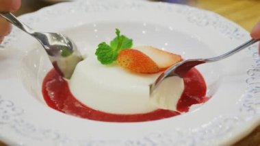 yakın çekim. eller aynı anda iki taraftan Panna Cotta tatlı bir dilim koparmak. restoranda.