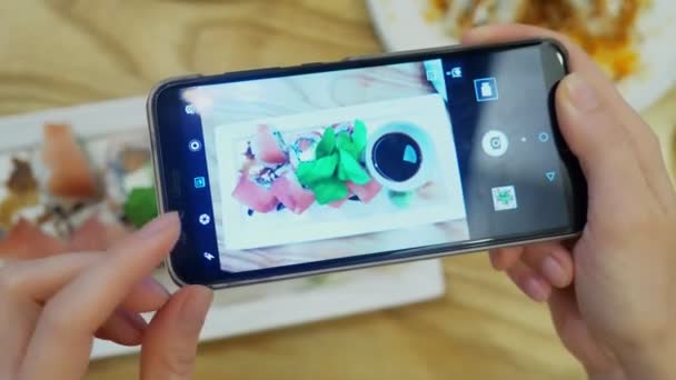 Yakın çekim. Eller bir smartphone cep telefonu ile bir restoranda suşi fotoğrafını çekin. — Stok video