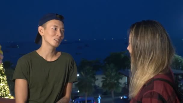 Молодая красивая азиатская пара, парень и девушка разговаривают друг с другом, стоя на улице города — стоковое видео