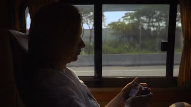 Bir minibüs yolcu koltuğunda otururken bir kadının telefon kullanır. — Stok video