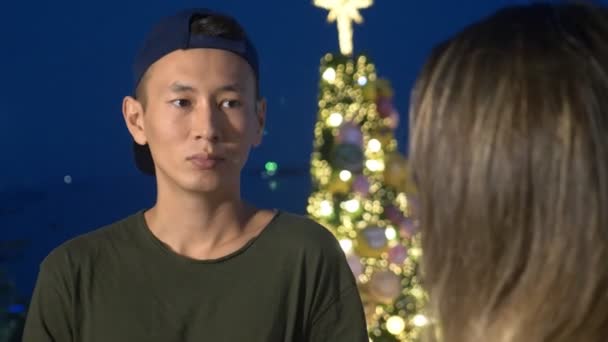 Молодая красивая азиатская пара, парень и девушка разговаривают друг с другом, стоя на улице города — стоковое видео