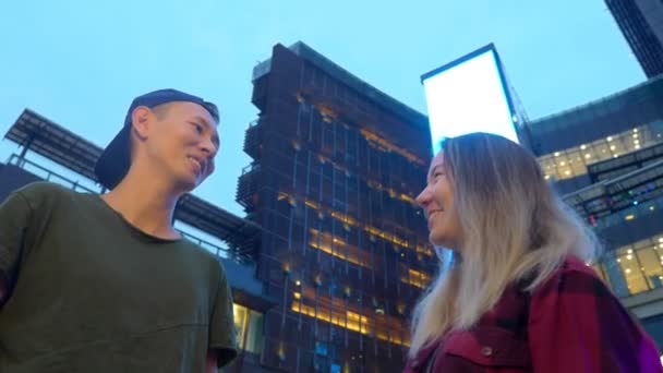 Joven hermosa pareja asiática, chico y chica están hablando entre sí, de pie en la calle de la ciudad — Vídeo de stock