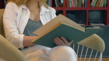 Genç kadın kütüphanede kitap rafı arka plan üzerine bir kitap okuma