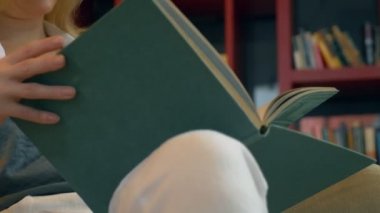 Genç kadın kütüphanede kitap rafı arka plan üzerine bir kitap okuma
