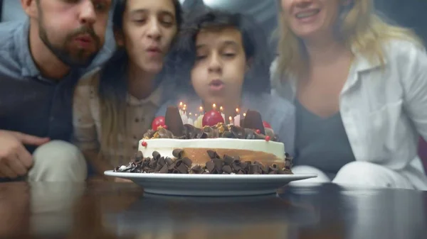 Feliz chico sonriente soplando velas en su pastel de cumpleaños. niños rodeados de su familia. pastel de cumpleaños con velas — Foto de Stock