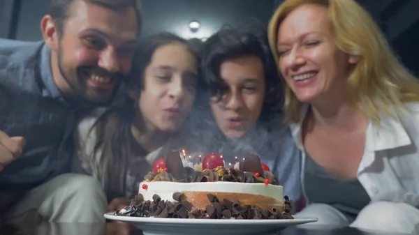 Felice ragazzo sorridente che soffia candele sulla sua torta di compleanno. bambini circondati dalla loro famiglia. torta di compleanno con candele — Foto Stock