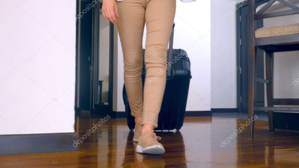 close-up, female legs in sneakers, suitcase. woman with luggage enters the hotel room suite