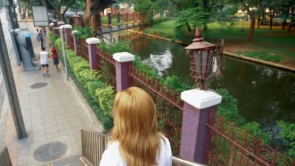 Bájos fiatal nő, aranyló hajjal, séta a központ a város, ő sétál át a hídon — Stock videók