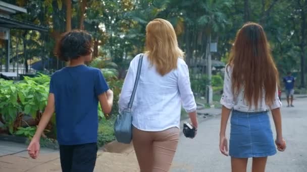 Mujer con hijos, hijo e hija adolescentes con una cámara camina por las calles de una gran ciudad moderna — Vídeo de stock