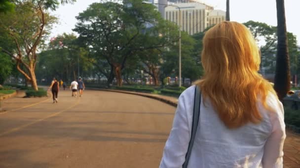 Encantadora joven con el pelo dorado corriendo en el centro de la ciudad . — Vídeos de Stock