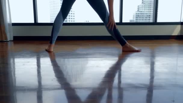 Young woman doing yoga in a room near a large window overlooking the skyscrapers. — Stock Video