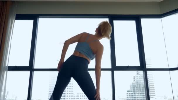 Jeune femme faisant du yoga dans une chambre près d'une grande fenêtre donnant sur les gratte-ciel . — Video