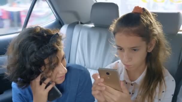 Tvillingar bror och syster använda telefonen medan man reser i bilen — Stockvideo