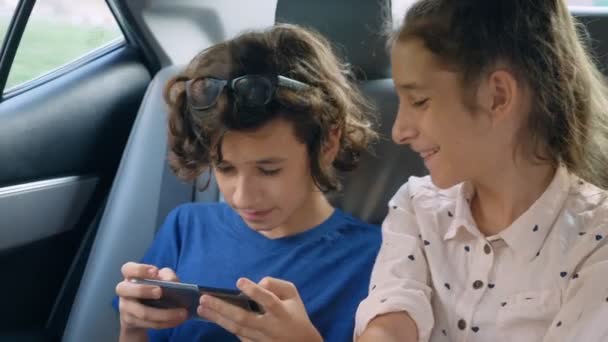 双胞胎兄妹在车里旅行时使用电话 — 图库视频影像