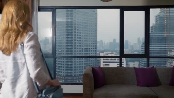 Pareja atractiva, mujer y hombre con una maleta en el fondo de rascacielos en una ventana panorámica por la noche — Vídeo de stock
