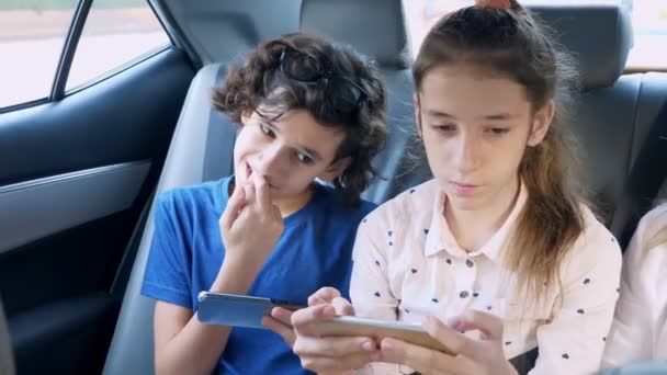 Gemelos hermano y hermana utilizar el teléfono mientras viaja en el coche — Vídeos de Stock