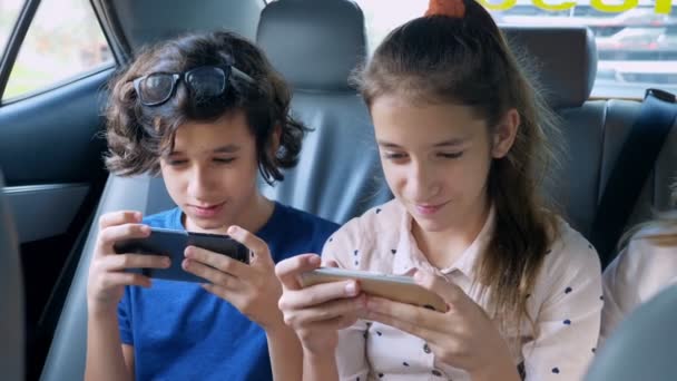 Twins brother and sister use the phone while traveling in the car — Stock Video