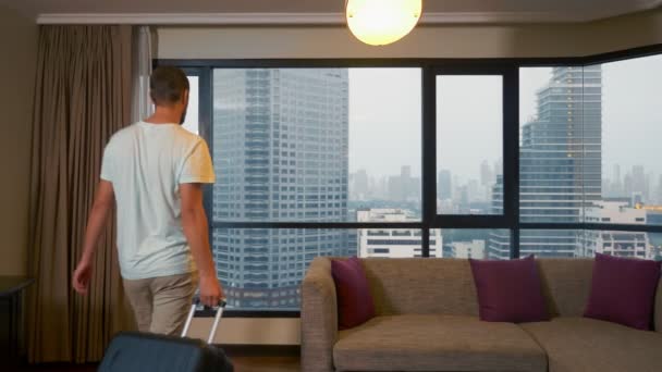 Hombre con una maleta en el fondo de rascacielos en una ventana panorámica — Vídeos de Stock