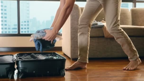 Красивый мужчина упаковывает чемодан в комнате с панорамным окном с видом на небоскребы — стоковое видео