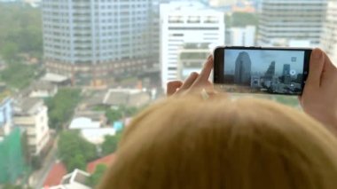 Zarif sarışın kadın telefonda bir fotoğraf yapmak. gökdelen penceresinden görünümü kadın fotoğrafları