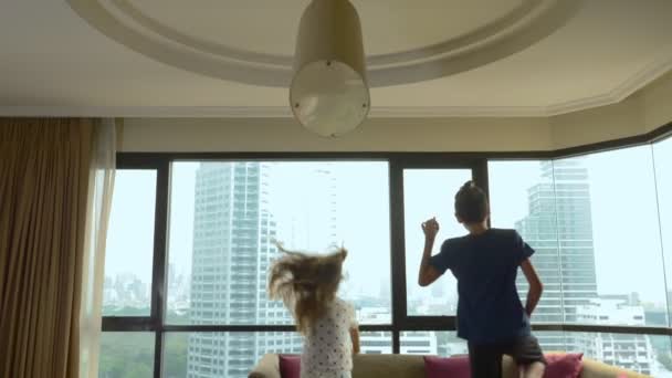 Glückliche Familie, Frau, Mann und zwei Kinder mit einem Koffer vor dem Hintergrund von Wolkenkratzern in einem Panoramafenster — Stockvideo