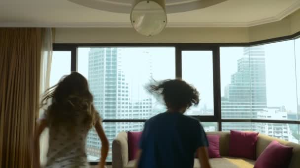 Familia feliz, mujer, hombre y dos niños con una maleta en el fondo de rascacielos en una ventana panorámica — Vídeos de Stock