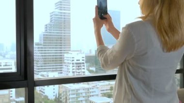 Zarif sarışın kadın telefonda bir fotoğraf yapmak. gökdelen penceresinden görünümü kadın fotoğrafları