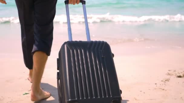 Бизнесмен с чемоданом отправляется на белый песчаный пляж. концепция фриланса, отпуск — стоковое видео