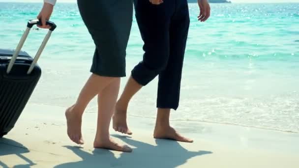 Hombre de negocios y mujer de negocios con una maleta caminando por la playa de arena blanca de la isla — Vídeo de stock