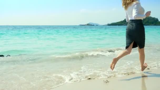 Mulher de negócios em roupas de escritório corre descalça para o mar ao longo de uma praia de areia branca. conceito de férias freelance, bem esperado — Vídeo de Stock