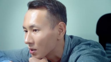 Genç yakışıklı Asya adam ofis masasında oturan onun laptop kullanma